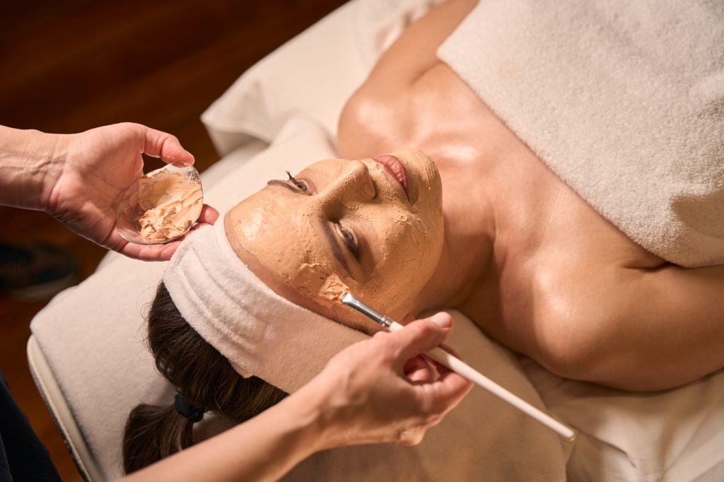 Qualified cosmetologist carrying out cosmetic procedure on adult woman